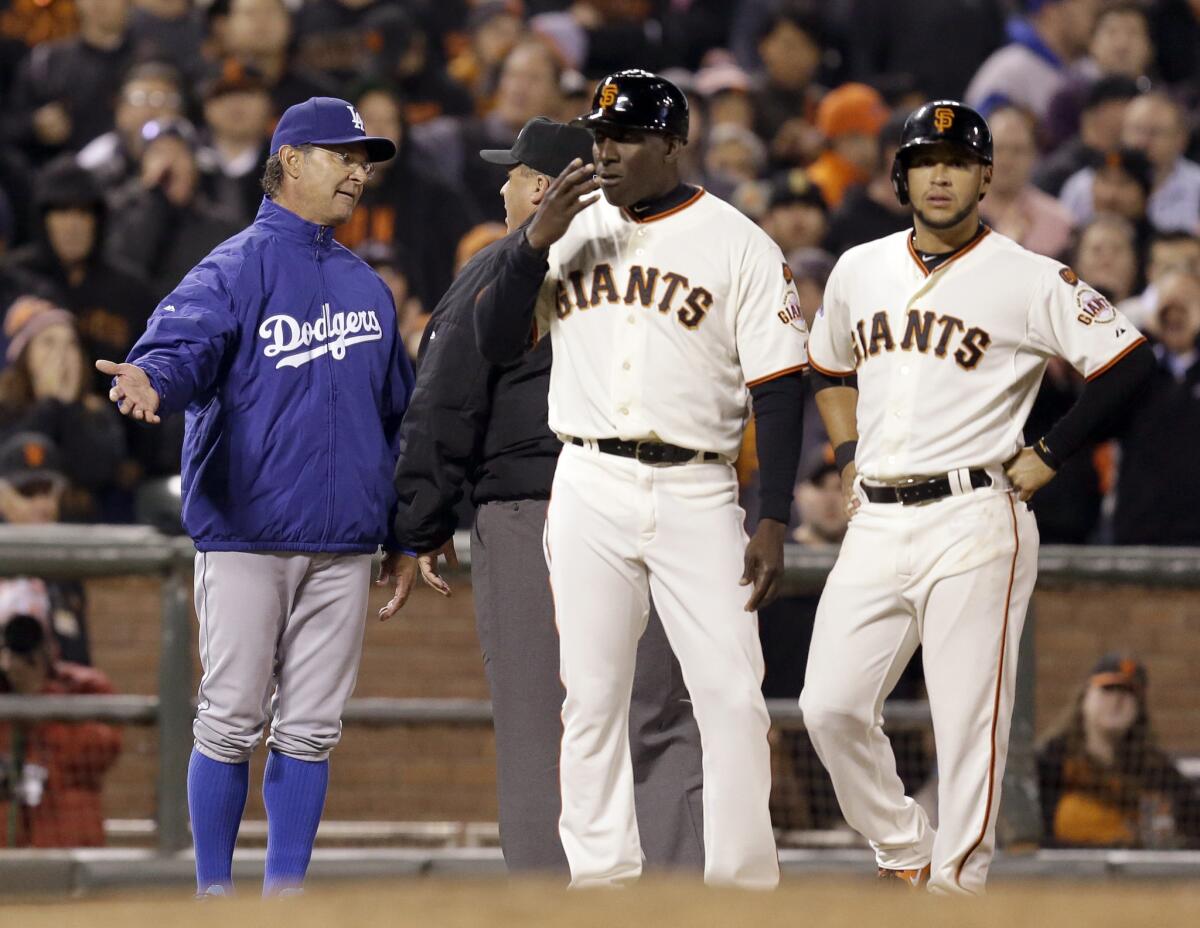 Dodgers Manager Don Mattingly argues with third-base umpire Fieldin Culbreth as San Francisco Giants third-base coach Roberto Kelly, middle, and Gregor Blanco, right, wait for a resolution in the ninth inning of an April 22 game in San Francisco.