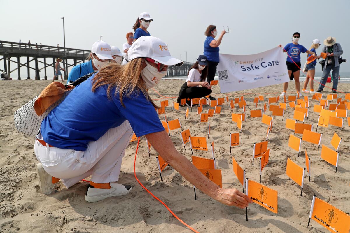 Patient Safety Movement Foundation members plant flags in the sand on Tuesday morning near the Newport Pier.