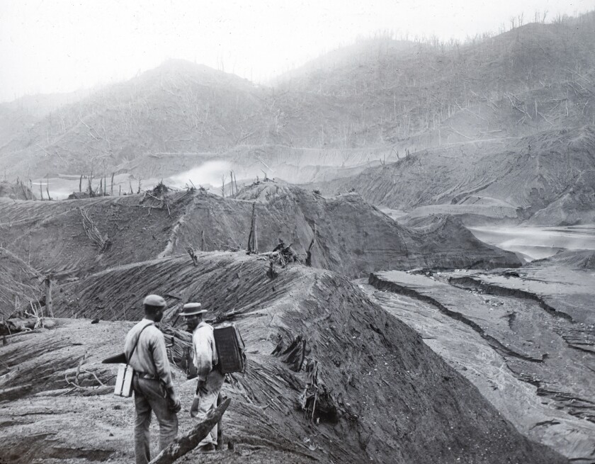 In this 1902 photo provided by York Museums Trust, men survey the devastation of the landscape following eruptions of La Soufrière, a volcano on the island of St. Vincent in the Caribbean. On April 9, 2021, La Soufriere once again started spewing hot torrents of gas, ash and rock, forcing thousands to evacuate to government-run shelters and private homes. (Tempest Anderson/York Museums Trust via AP)