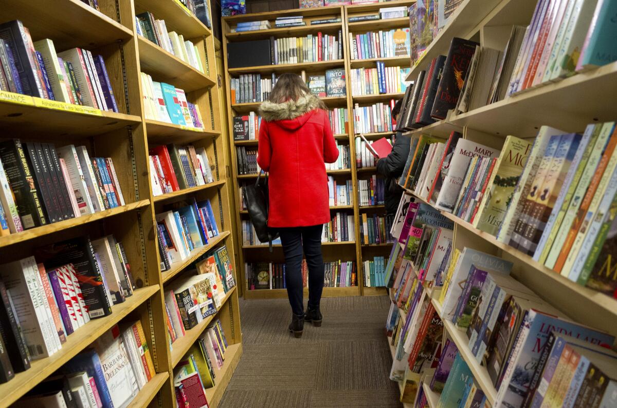 Shoppers browse among narrow rows of books