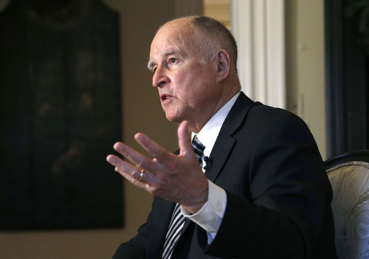 Closeup of Jerry Brown, in suit and tie, gesturing with one hand.