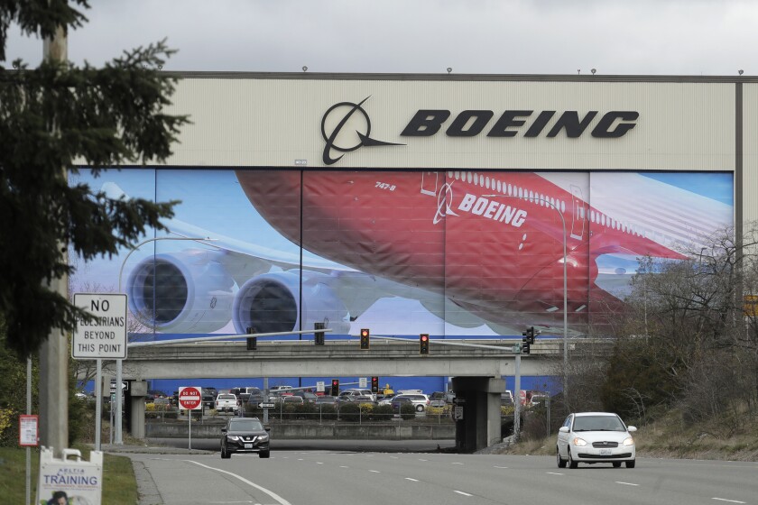 Cars drive near a Boeing factory in Everett, Wash., in March. Boeing says it will resume production of commercial airplanes in phases at its Seattle-area facilities next week.