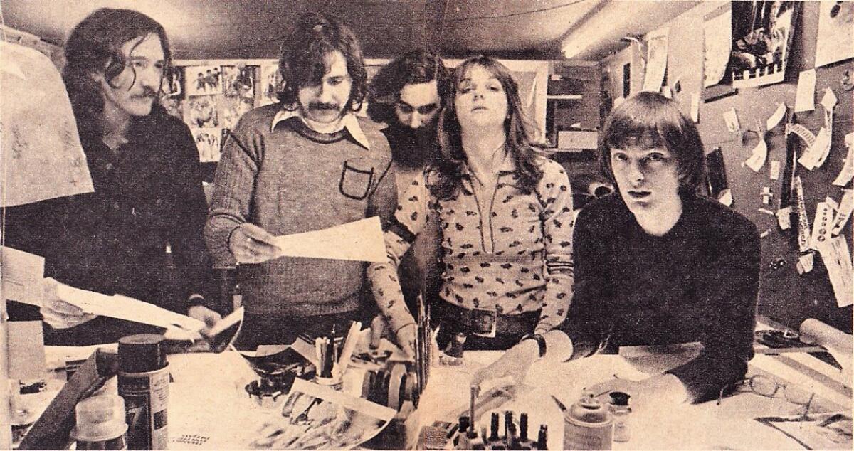 A sepia-toned photo of people putting out a magazine in the 1970s.