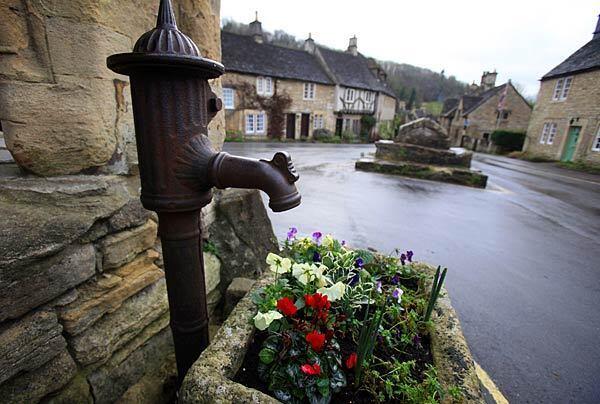 Flowers beneath the old village pump in Castle Combe's center.