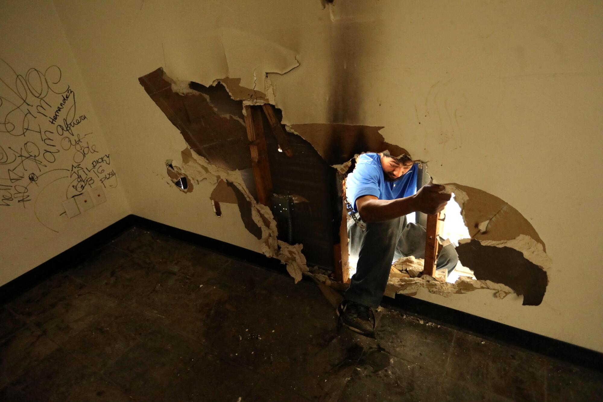 A man enters a building through a hole in the wall