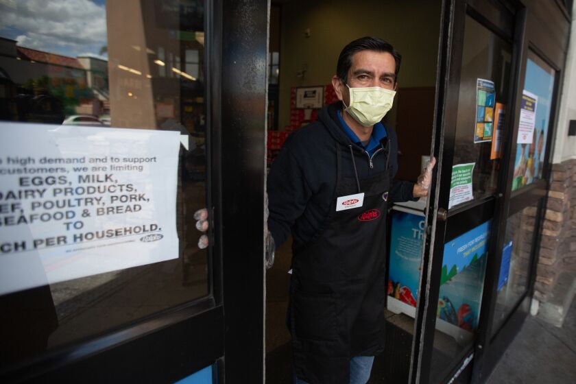 LOS ANGELES, CALIF. - MARCH 22, 2020: Enrique stands at the door of Ralphs grocery store in Westchester letting in only a few shoppers at a time on Sunday, March 22, 2020 in Los Angeles, Calif.. This Ralphs location is implementing social distancing guidelines for its customers. The store is placing social distancing markers every six feet and limiting the number of customers it allows in to shop to help with social distancing due to the Coronavirus pandemic. (Jason Armond / Los Angeles Times)