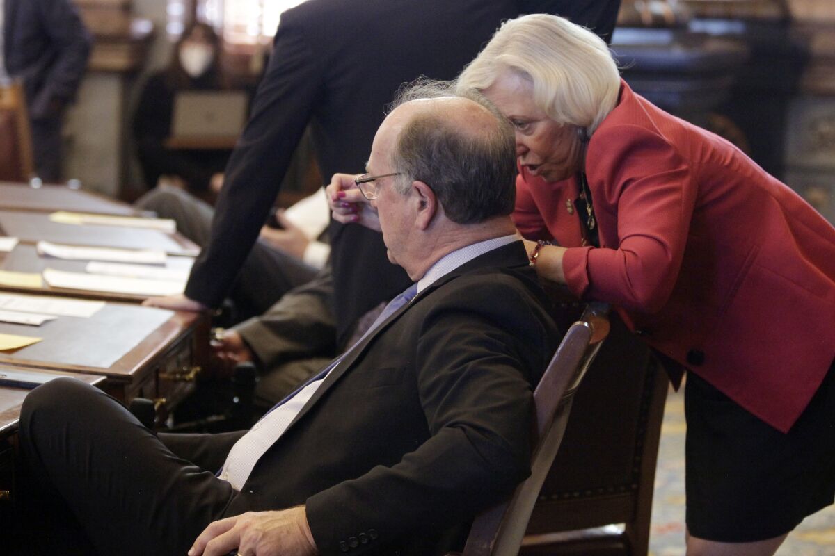 Kansas state Sens. Jeff Longbine, left, R-Emporia, and Pat Pettey, D-Kansas City, confer as the Senate votes on a measure to allow the state to offer more than $1 billion in breaks to an unnamed company to bring a $4 billion project to Kansas, Wednesday, Feb. 9, 2022, at the Statehouse in Topeka, Kan. Both Longbine and Pettey supported the measure, which is designed to seal a deal with the company to create 4,000 jobs. (AP Photo/John Hanna)