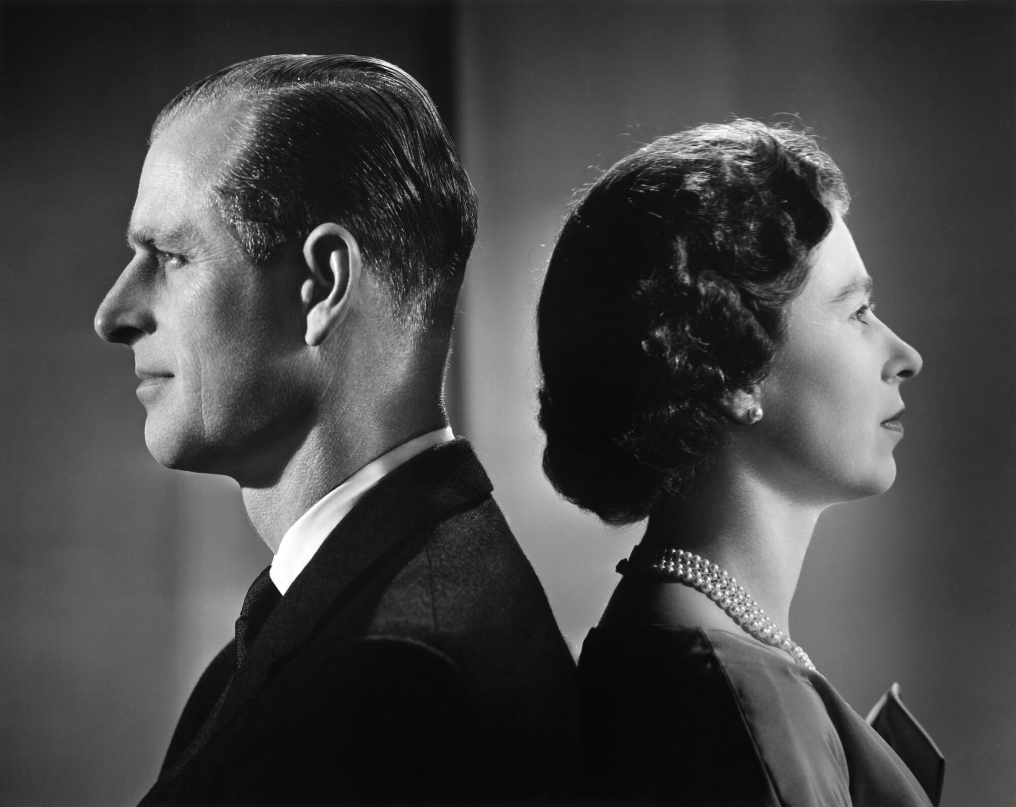 Queen Elizabeth II and Prince Philip stand back-to-back in a 1958 portrait