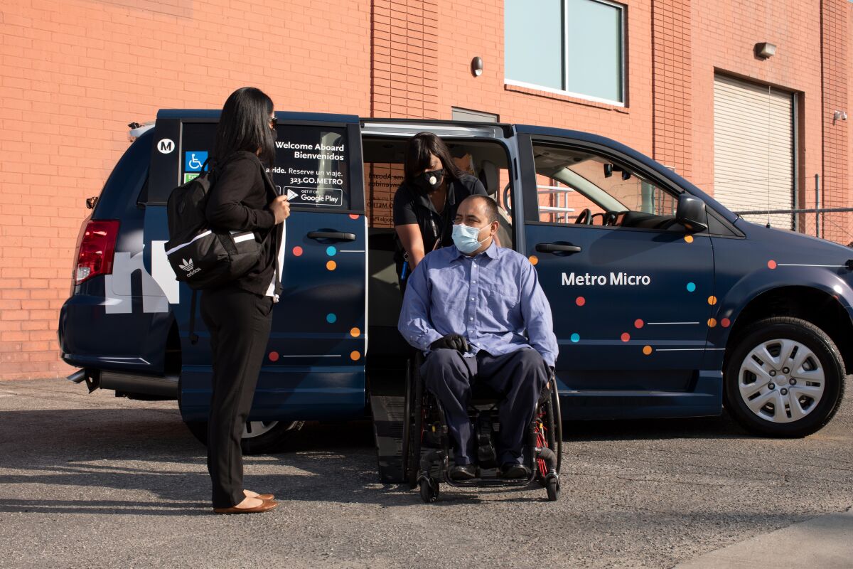 A man in a wheelchair is helped out of a Metro Micro minivan.