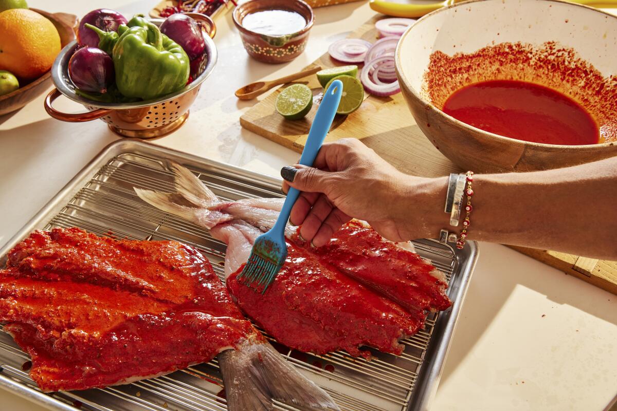 Rick Martinez brushes the achiote paste onto the red snapper.