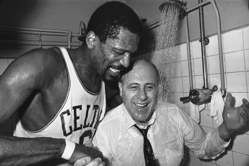 Bill Russell, left, of the Boston Celtics is shown as he holds his coach Red Auerbach under the shower.