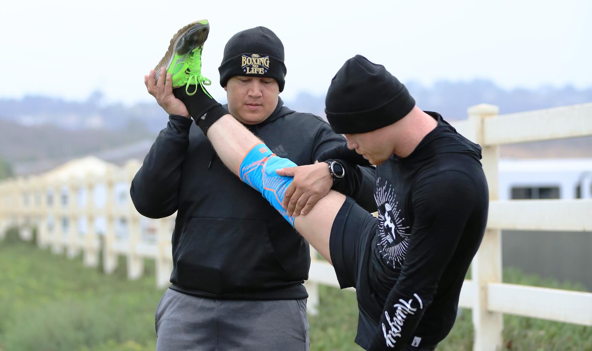 Eddy Reynoso, left, helps boxer Canelo ?lvarez stretch at his training facility in San Diego.