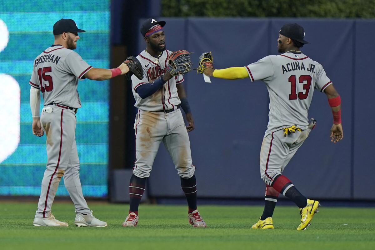 Atlanta Braves left fielder Robbie Grossman (15) center fielder Michael Harris II (23) and right fielder Ronald Acuna Jr. (13) celebrate after the Braves beat the Miami Marlins 5-2 during the first game of a baseball doubleheader, Saturday, Aug. 13, 2022, in Miami. (AP Photo/Wilfredo Lee)