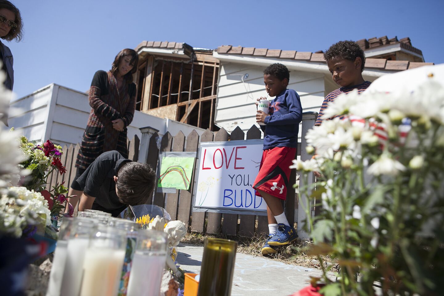 Visitors view a roadside memorial for an 8-year-old boy who was hit and killed by a truck Wednesday at 15th Street and Michael Place in Newport Beach.