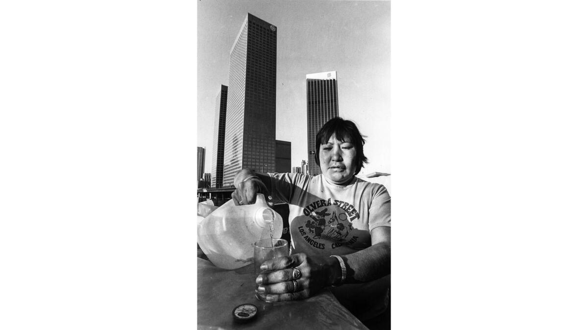 Feb. 5, 1984: Wilma Aros pours herself a glass of water from a plastic jug at a makeshift shelter on Bunker Hill.