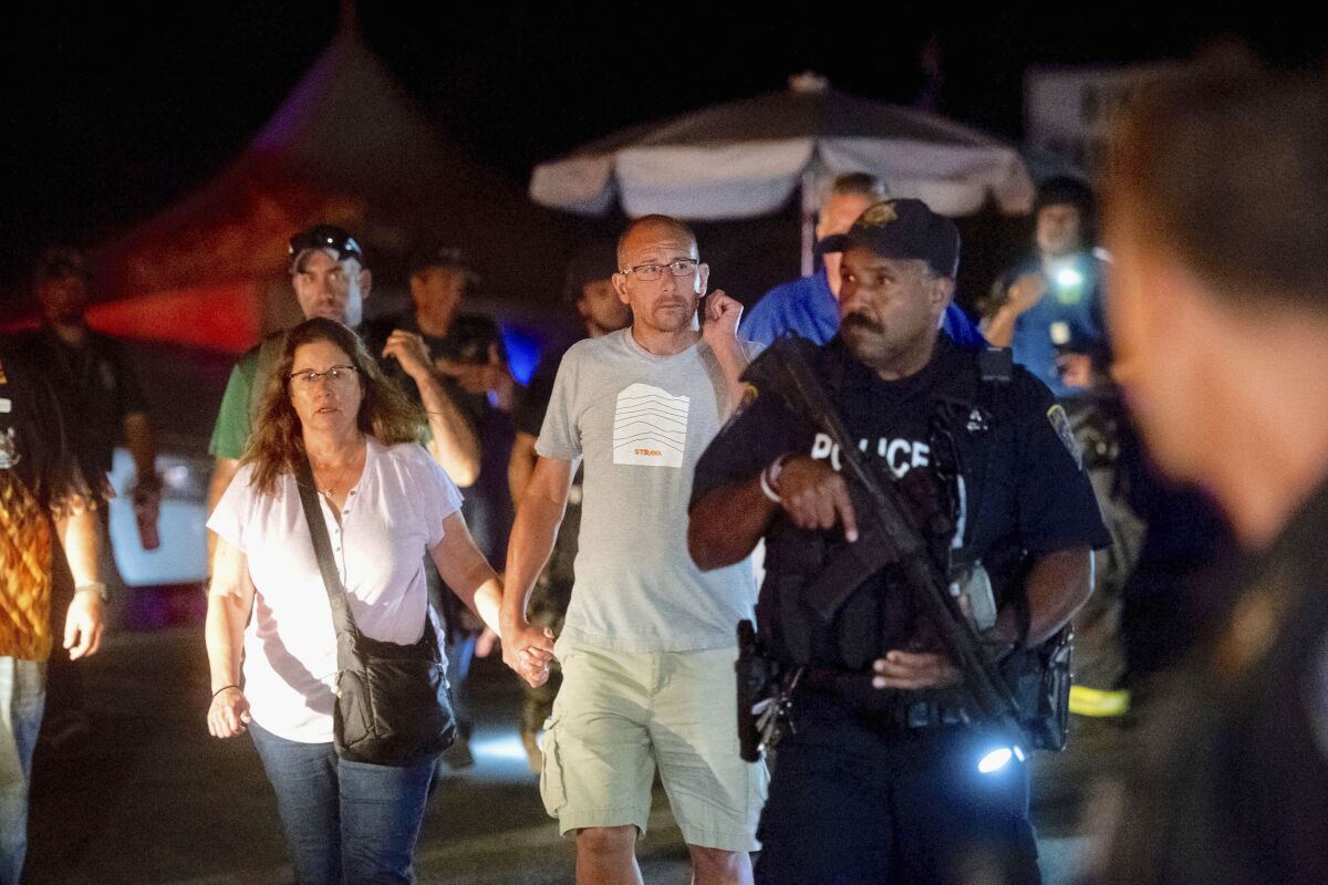 Police officers escort people from the festival grounds after the shooting July 28.