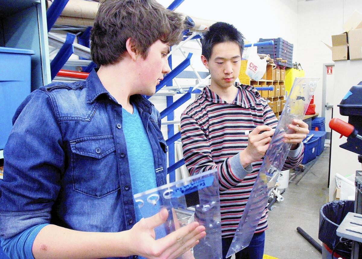 Alex McComb, 16, and club president Philipp Wu, 16, prepare pieces of their backup robot for drilling on the drill press at La Cañada High School on Tuesday, March 11, 2014.