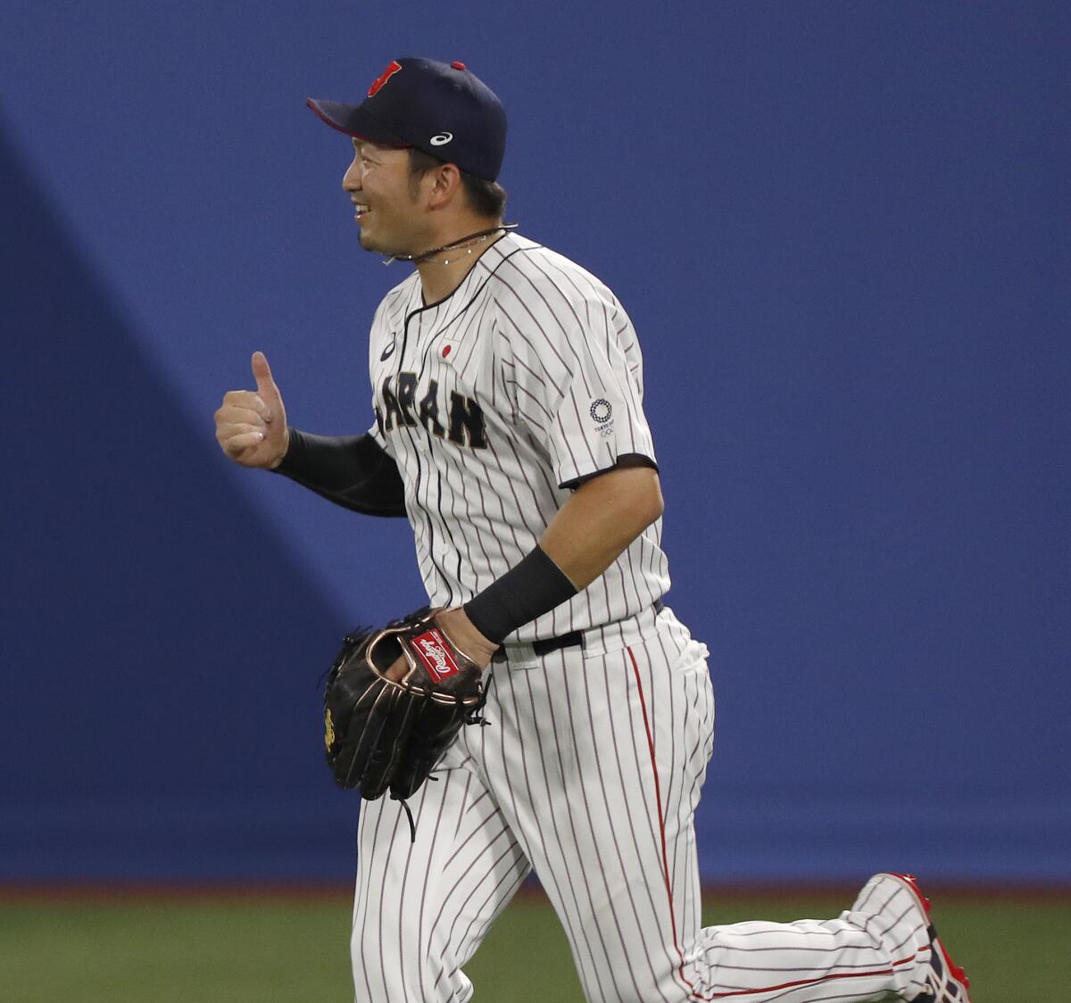 Japan outfielder Seiya Suzuki gives a thumbs up while running on the field