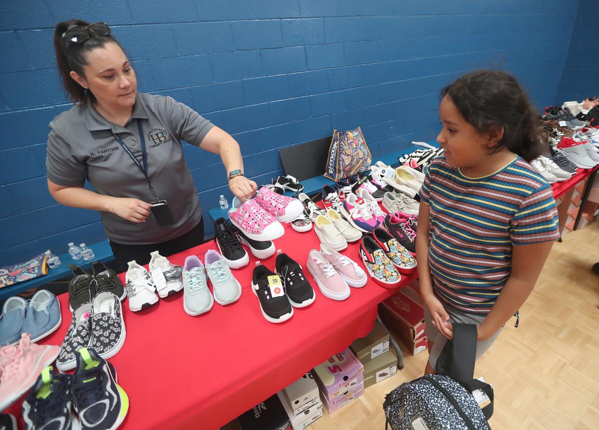 Volunteer Hayley Yantorn, Huntington Beach Police Department community relations specialist, offers a pair of shoes.