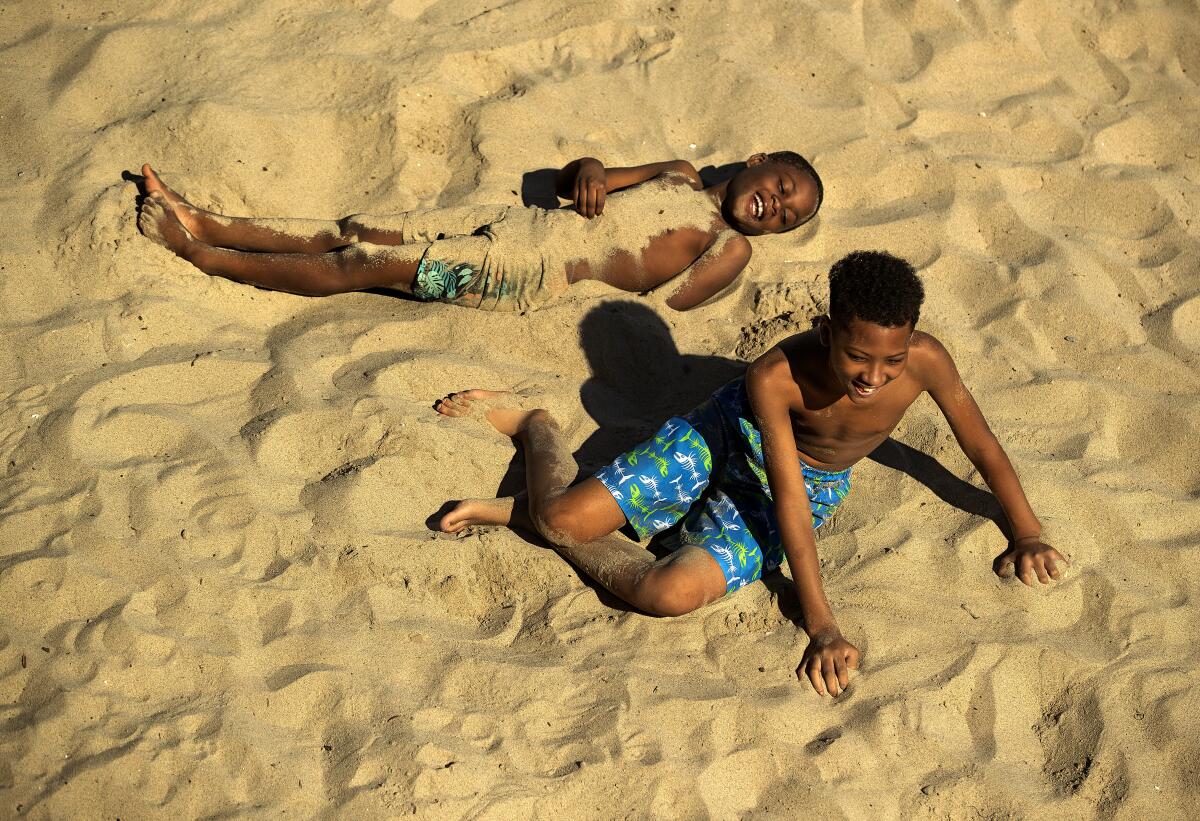Montey Taylor, 7, top, and his cousin Darryl Bing, 12, play in the sand at a Santa Monica beach.