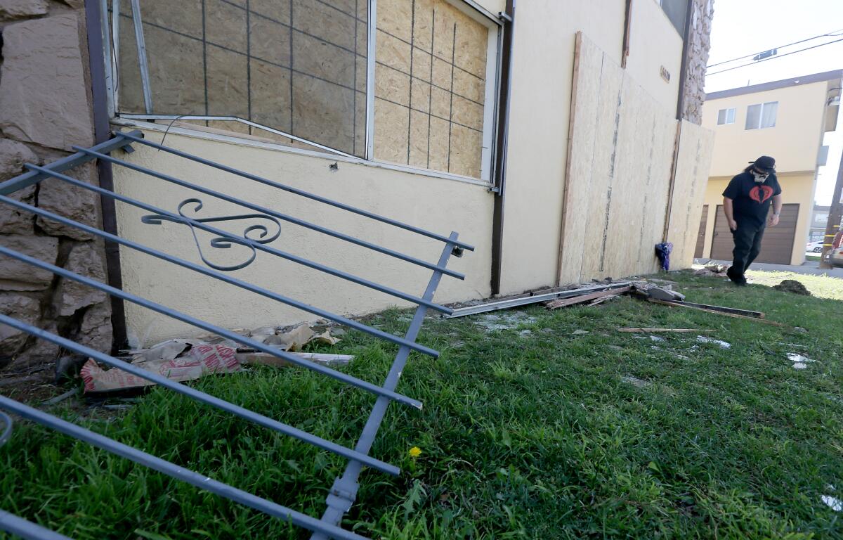 A man leaves flowers outside a boarded-up building.