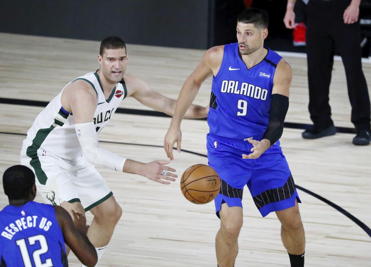 Magic center Nikola Vucevic passes the ball to forward Gary Clark while defended by Bucks center Brook Lopez during Game 1.