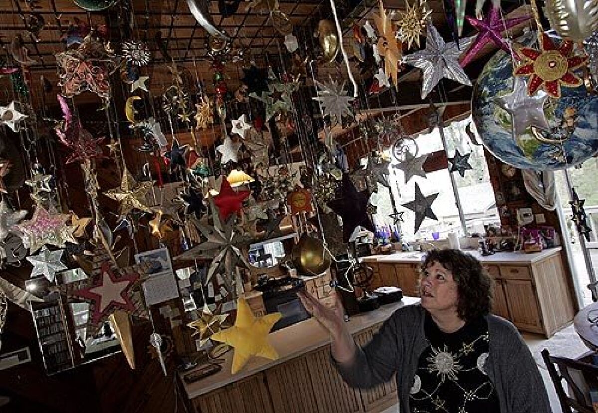 Kara Knack, in the dining room of her Malibu home, shows some of the moons, stars and suns in her huge collection. She's donated more than 2,000 celestially themed jewelry pieces to Griffith Observatory, which has arranged them into an exhibit representing a timeline of the universe, all 13.7 billion years from the Big Bang to the present.