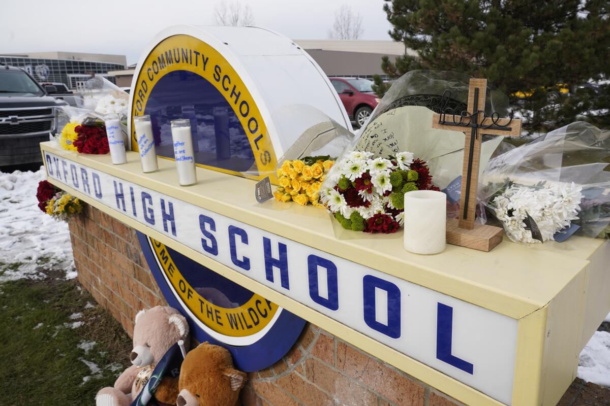 Flowers, candles and stuffed animals left as memorial on high school sign