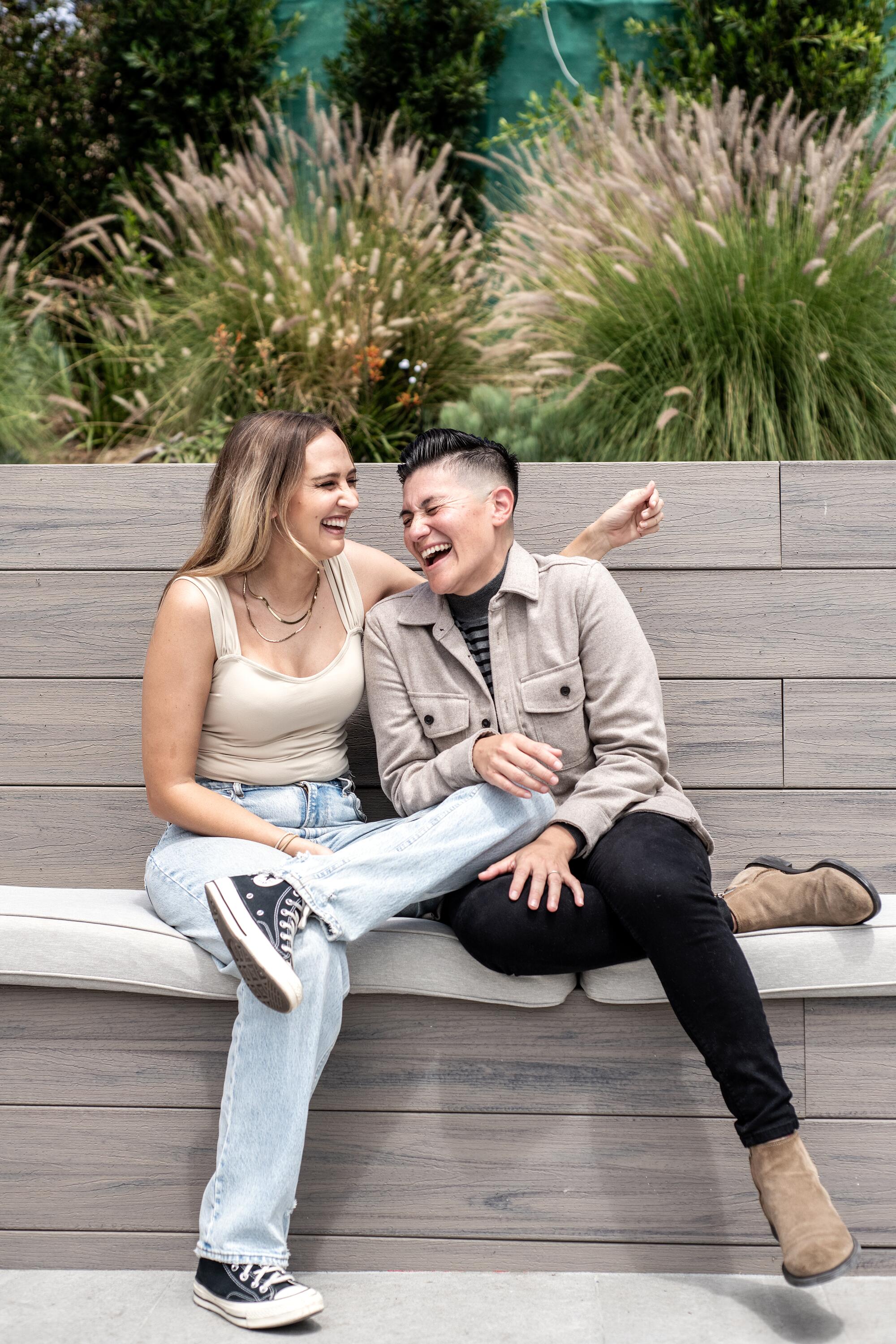 Two women laugh together on a bench