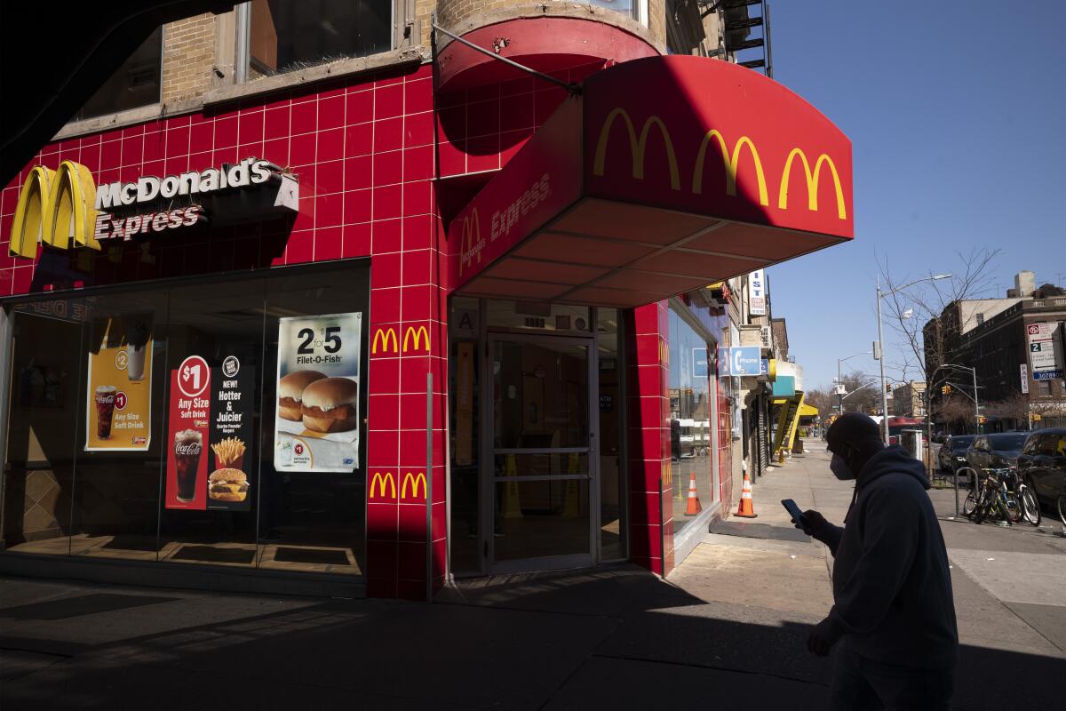 A customer wearing a mask passes a McDonald's restaurant in Brooklyn that is open for takeout service.