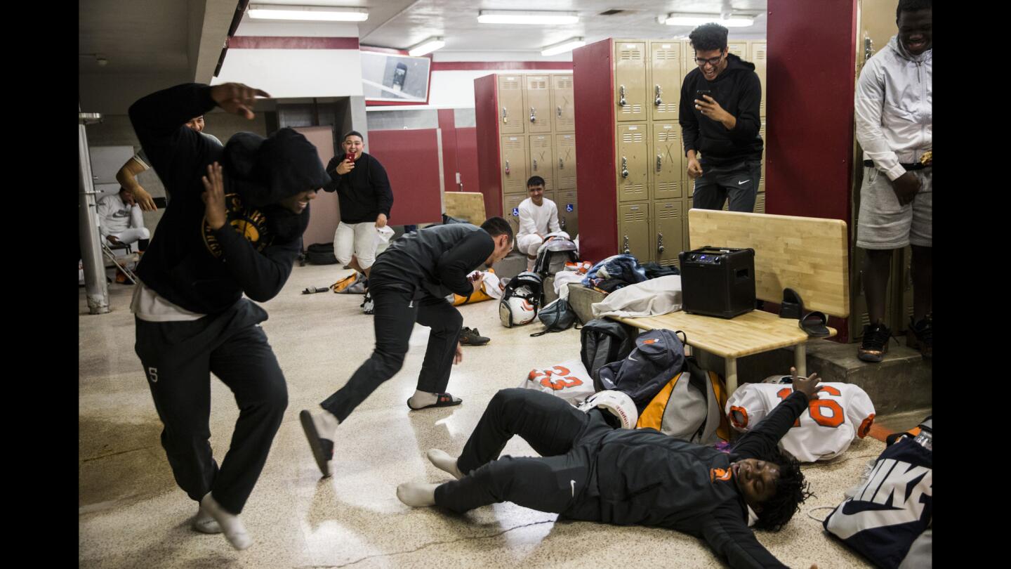 Bey'Jon Lee, Victor Molina, and James Rossum react to James falling during a pregame dance battle in the locker room.