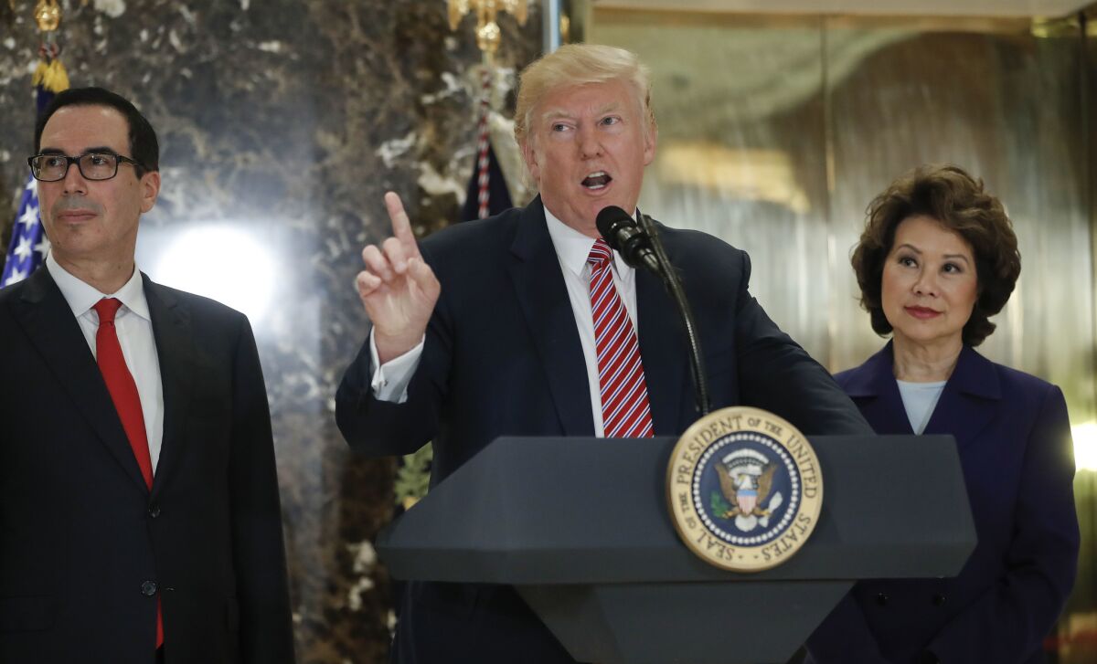 Transportation Secretary Elaine Chao, right, shown with Treasury Secretary Steve Mnuchin and President Trump, has brushed off suggestions for a federal regulation requiring masks on flights.