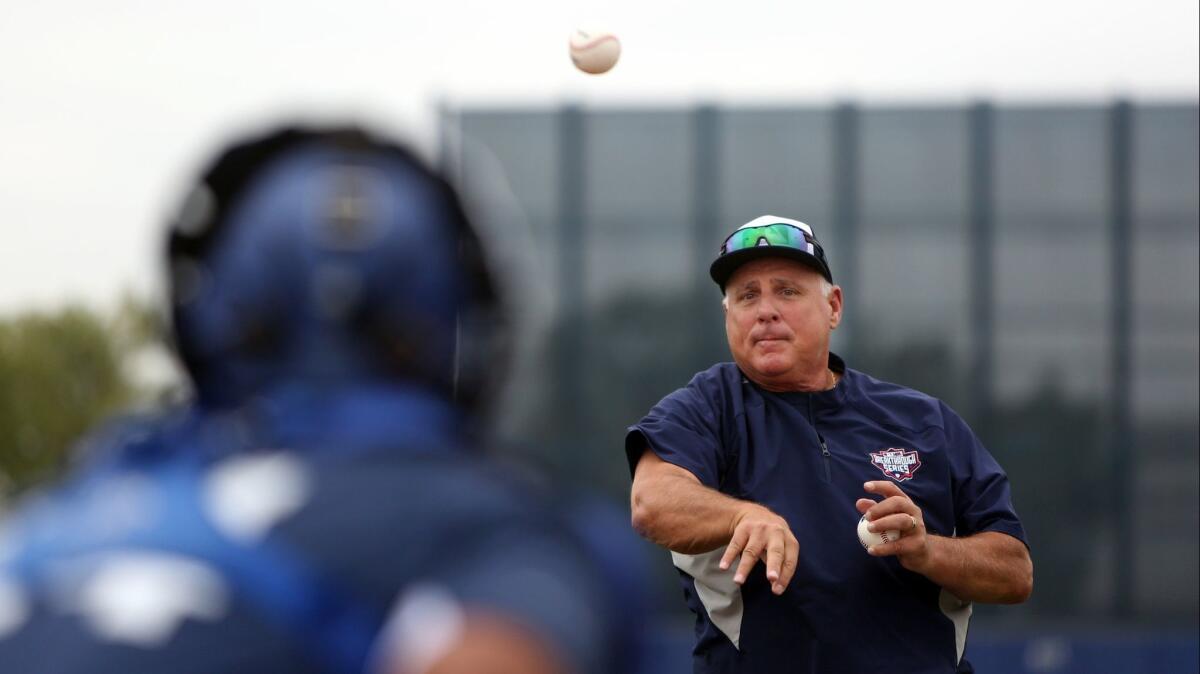 Mike Scioscia tosses the ball to catchers training at the Major League Baseball Youth Academy on Saturday in Los Angeles.