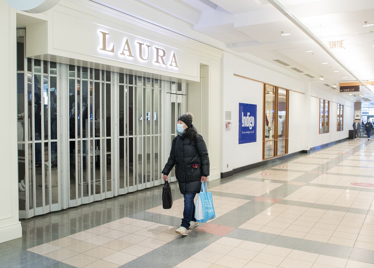 A woman walks by a closed store in a mall in Montreal, Sunday, Jan. 2, 2022, as the COVID-19 pandemic continues in Canada. Some measures put in place by the Quebec government, including the closure of stores, go into effect today to help curb the spread of COVID-19 in the province. (Graham Hughes /The Canadian Press via AP)