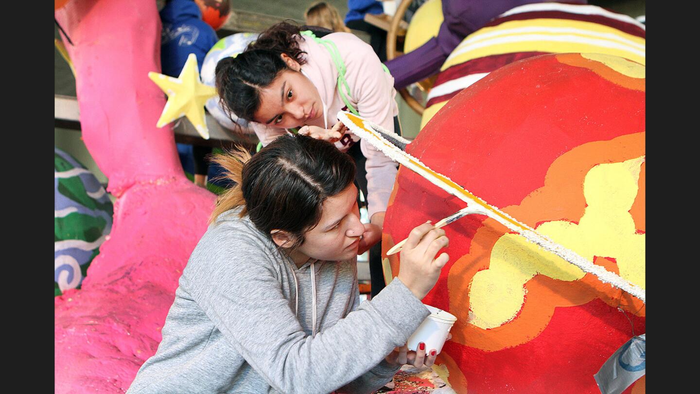 Highland Park friends Ariana Aguirre, bottom, and Sarah Maciel apply glue and seeds to the ring of a planet on the La Cañada Flintridge Rose Parade float in the parking lot for Flintridge Prep in La Cañada Flintridge on Wednesday, December 28, 2016. The float theme is "Backyard Rocketeer" and is covered with animation.