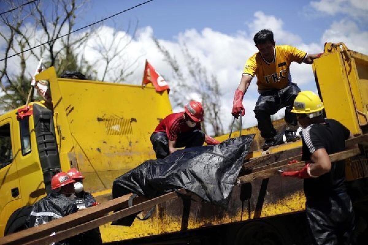 Workers load another body onto a truck for burial in a mass grave in Tacloban, Philippines, on Friday.