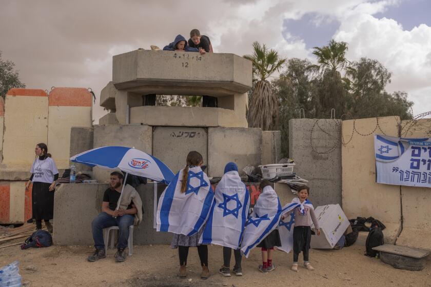 Varias personas esperan junto al paso fronterizo israelí de Nitzana, en la frontera con Egipto, el 27 de febrero de 2024 en protesta por la entrada de ayuda humanitaria a Gaza sin que se haya liberado a todos los rehenes capturados por Hamás. (AP Foto/Ohad Zwigenberg)