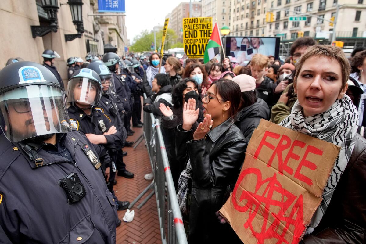 Police in riot gear stand guard near protesters outside the Columbia University campus in New York on April 18.