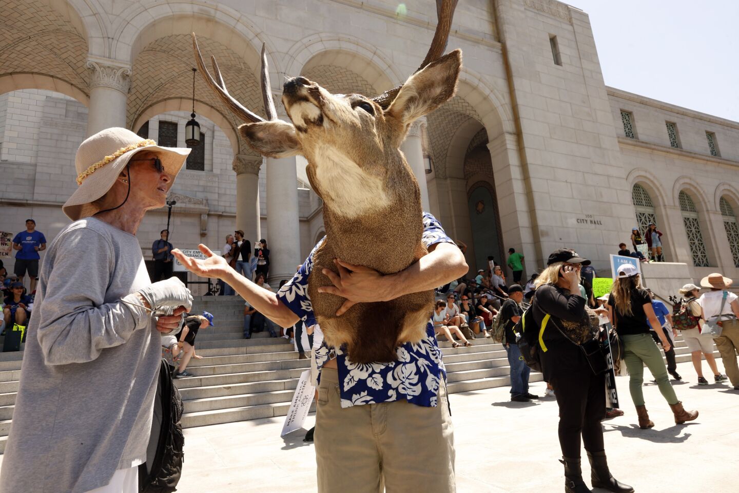 Mike Gloria, 58, holding a deer's head, enjoys a conversation in front of City Hall at the end of the March for Science.