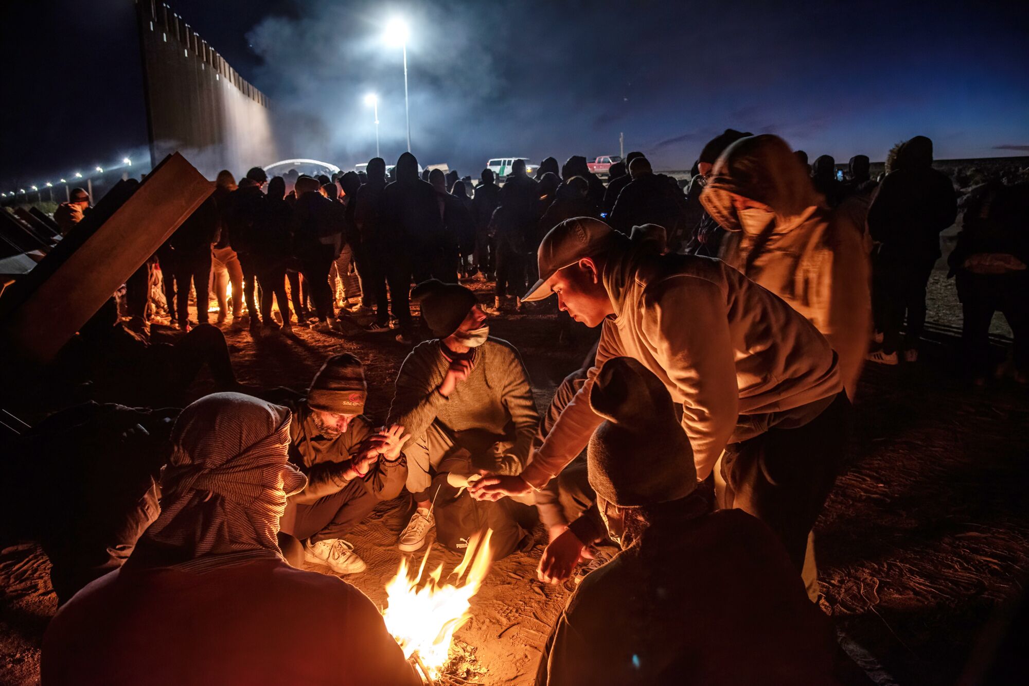 Migrants who crossed the border without authorization in the frigid early morning huddle around makeshift fires.