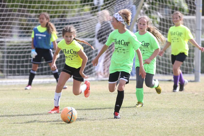 Newport Coast Elementary's Elisabeth Thomas, left, begins to dribble upfield as Huntington Beach Pegasus' Katherine Janda comes in to defend in a girls’ fifth- and sixth-grade Silver Division pool-play match at the Daily Pilot Cup on Friday at Jack R. Hammett Sports Complex in Costa Mesa.