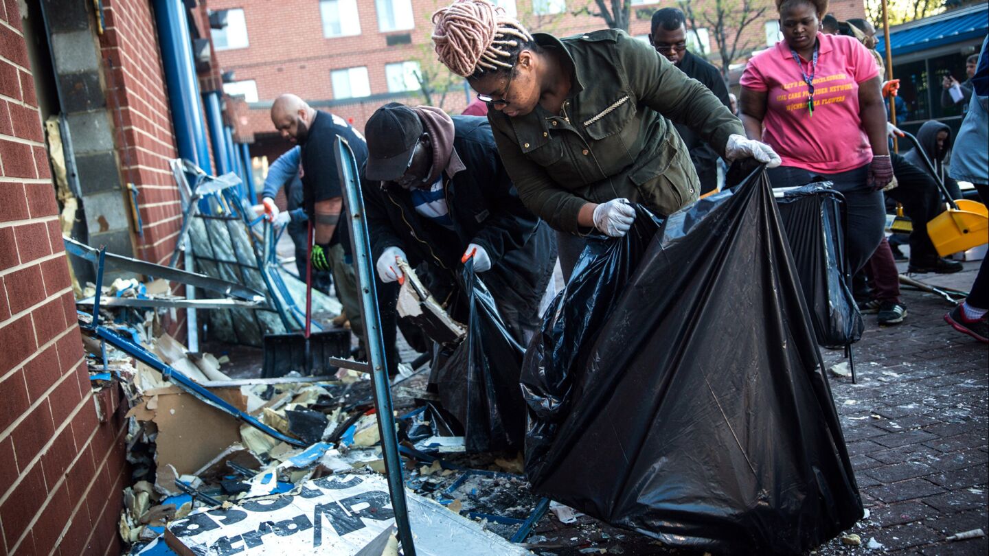 Members of the community clean up debris from a CVS pharmacy that was set on fire Monday during rioting after the funeral of Freddie Gray in Baltimore.