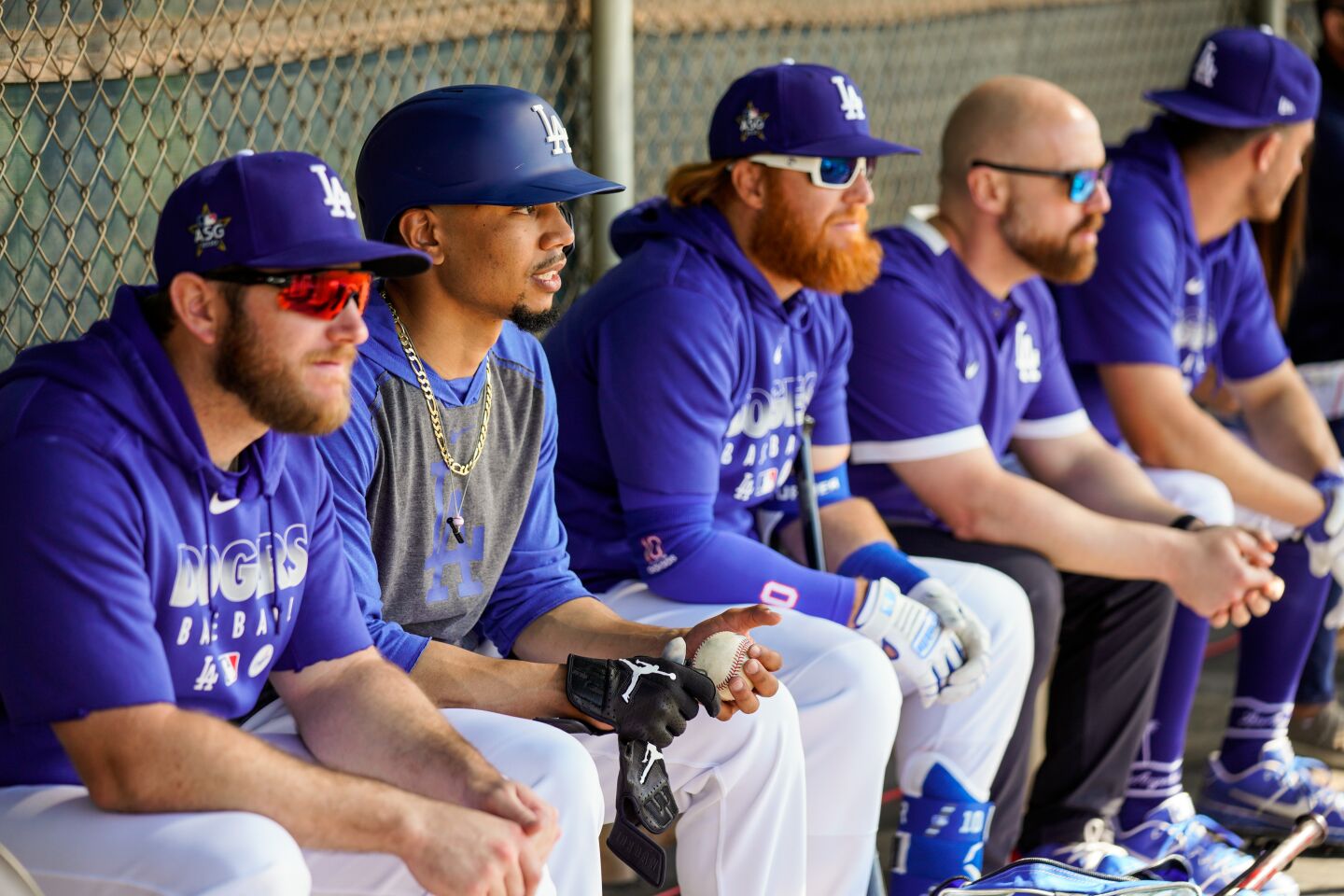 Dodgers players, including from left, Max Muncy, Mookie Betts and Justin Turner, sit in a dugout during a practice at Camelback Ranch.