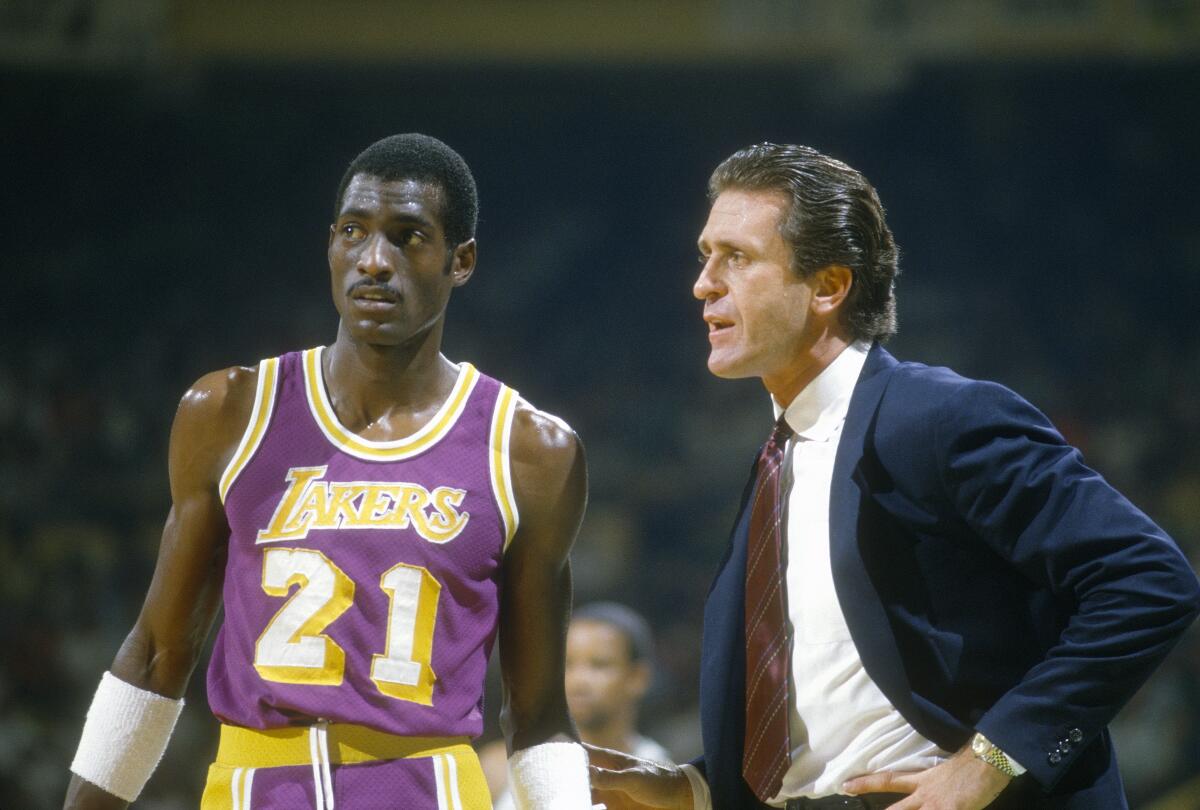 Lakers standout Michael Cooper, left, speaks with coach Pat Riley during a game in 1985.