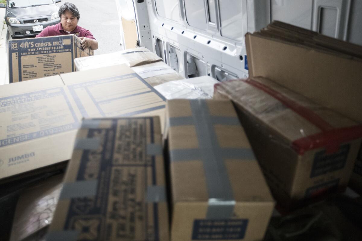 Caburog loads a box into his truck for customers shipping to family in the Philippines while on his route in Carson, Calif. (Brian Van Der Brug / Los Angeles Times)