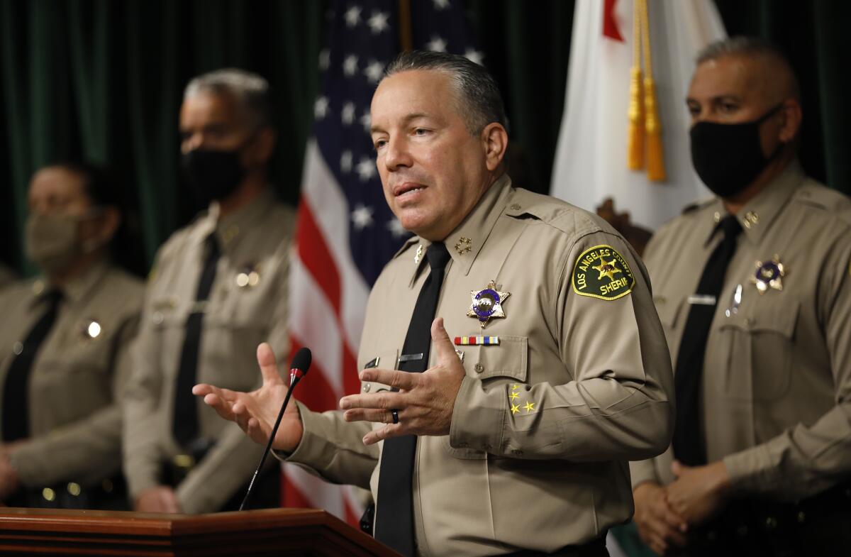 A man in a law enforcement uniform speaks at a lectern.