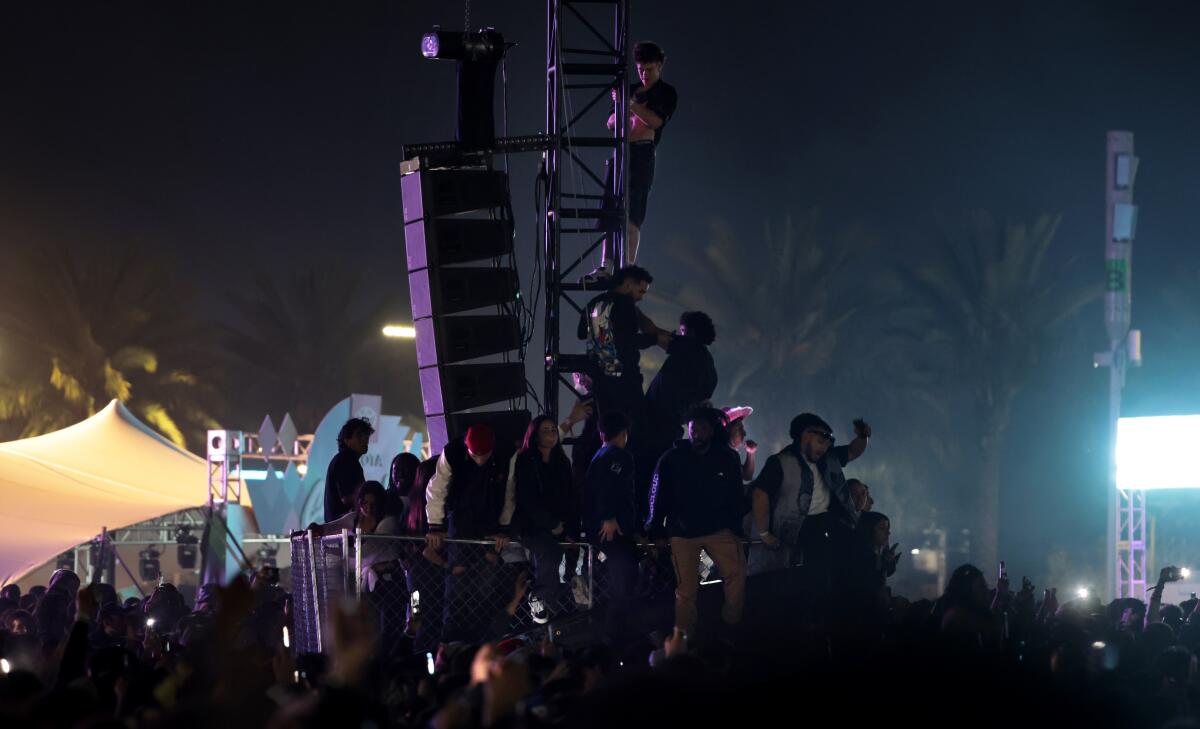 Fans climb a structure to watch Kanye West perform Thursday at Rolling Loud.