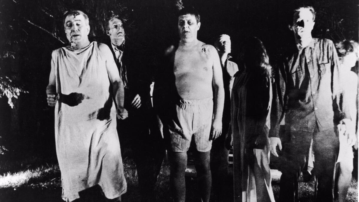 A line of undead 'zombies' walk through a field in "Night Of The Living Dead."