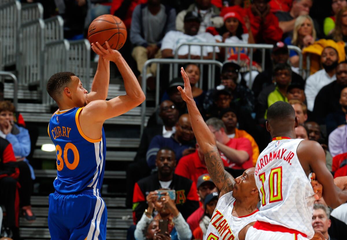 Warriors guard Stephen Curry (30) shoots a three-point basket over Hawks guard Jeff Teague.