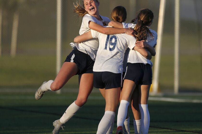 Marina's Kayden Smith (19) is mobbed by teammates including Samantha Esparza, left, after tying the game during Wave League girls' final soccer match against Corona del Mar on Wednesday.